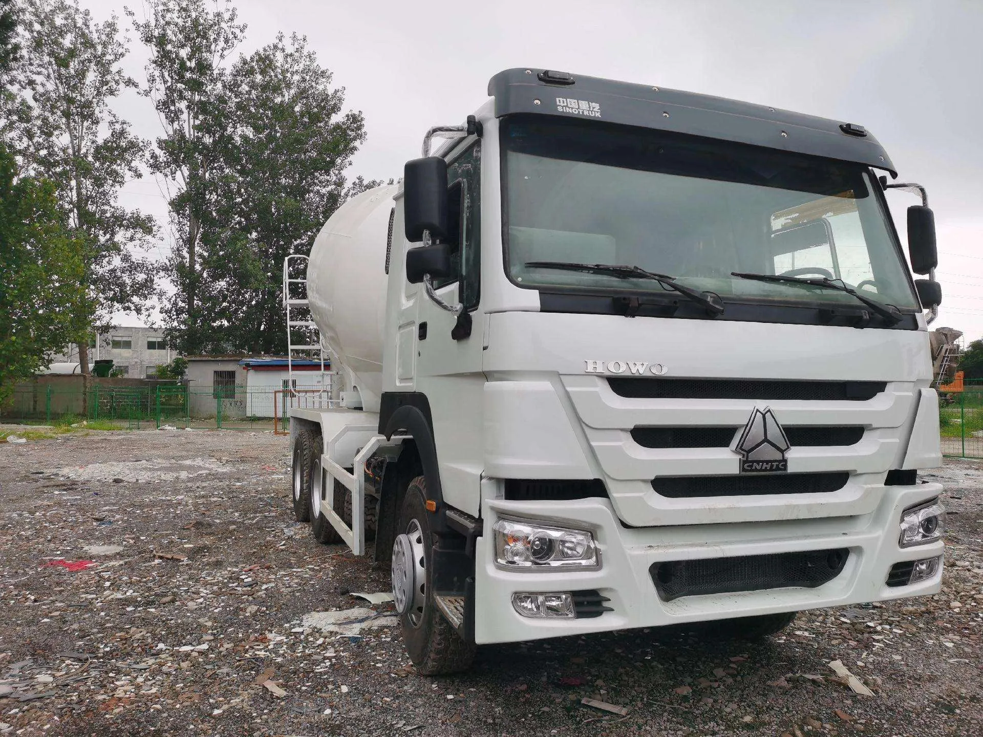 White HOWO concrete mixer truck, front three-quarter view parked in the yard