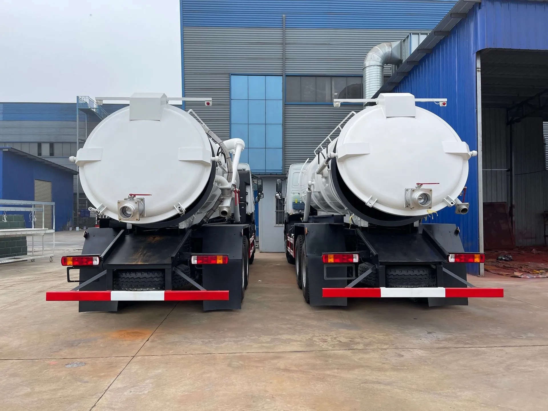 Rear view of two sewage tankers showing the ball-valve discharge outlets and rear underrun bars