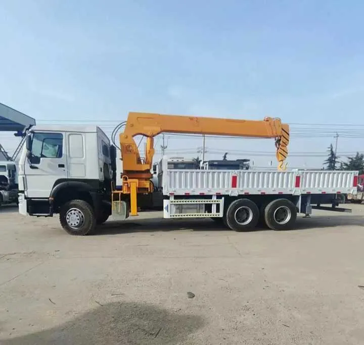 White and black 6x4 truck mounted crane, side profile, boom stowed, parked in a paved yard