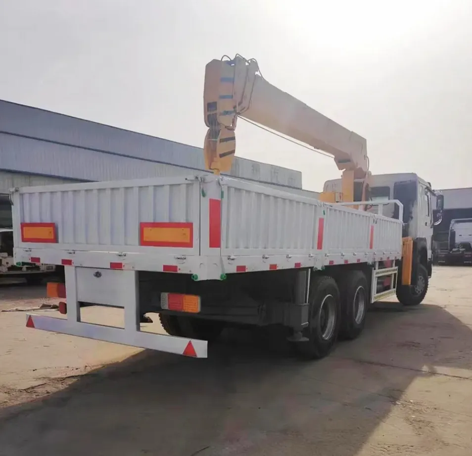 White 6x4 cargo truck with the yellow crane boom folded above the bed, rear three-quarter view in an outdoor yard