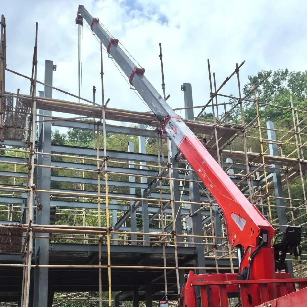 Red knuckle-boom crane extended over a scaffolded steel-frame building under construction