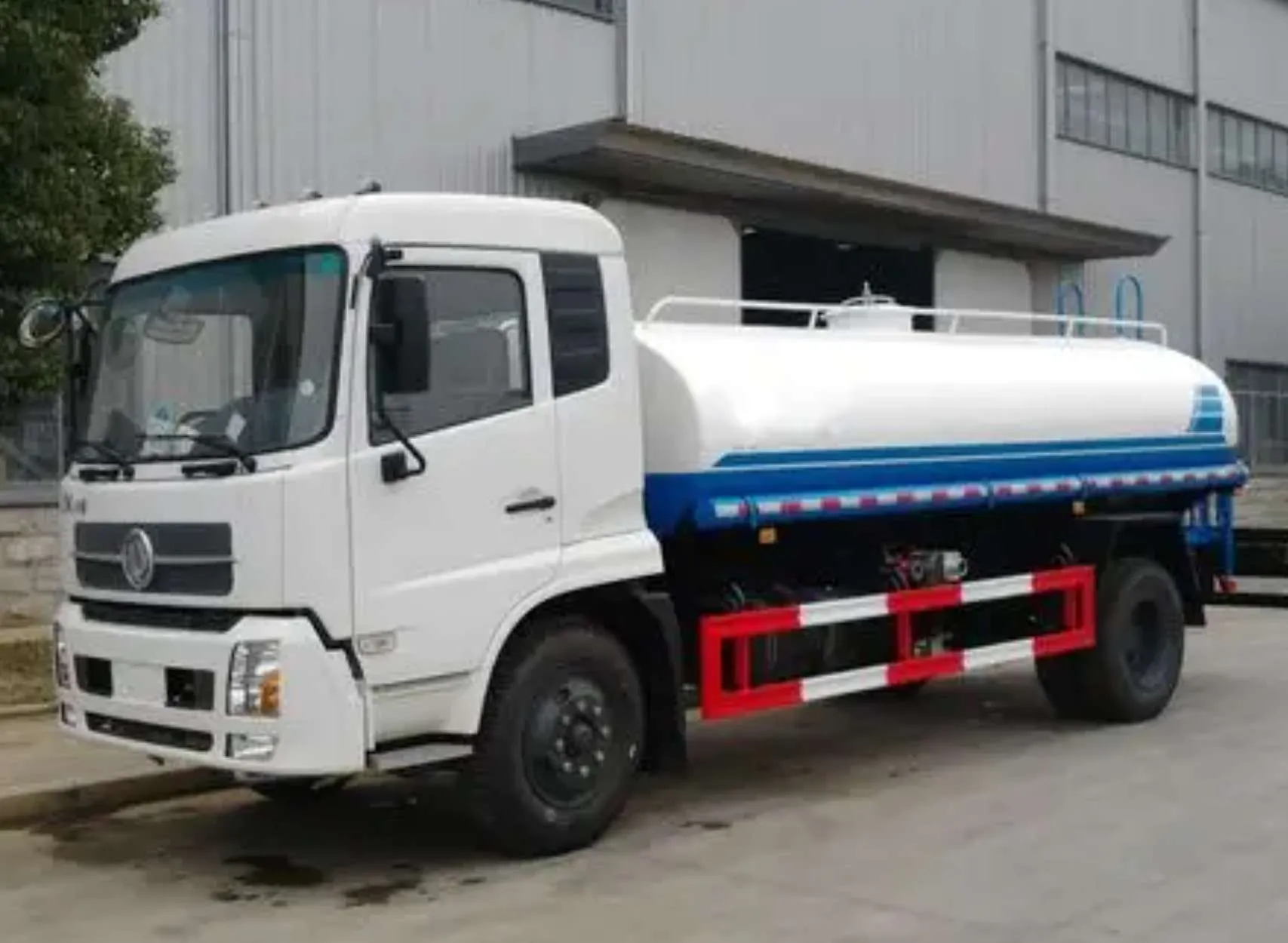 Dongfeng chassis water tank truck with blue-striped tank, side three-quarter view outside the workshop